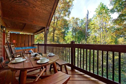 a wooden deck with a table and chairs on it at Kate's Cabin - 3 min to Dollywood! Cabin with Hot tub, Game Room, and Resort Pool! in Sevierville