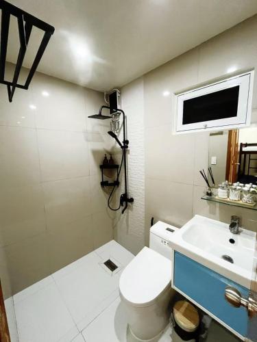 a bathroom with a toilet and a sink and a tv at C&G Staycation Home in General Trias