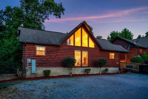 a log cabin with its lights on at Kate's Cabin - 3 min to Dollywood! Cabin with Hot tub, Game Room, and Resort Pool! in Sevierville