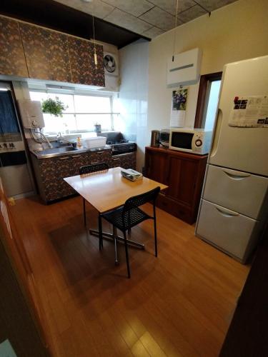 a small kitchen with a table and a refrigerator at Private Room in Japanese Vintage House 民家の一室 Smoke Free, Free Parking Good to Travel for Tashiro Cats Island no1 in Ishinomaki