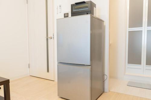 a refrigerator with a microwave on top of it at Laguna Verde Miyanosawa 102 in Sapporo