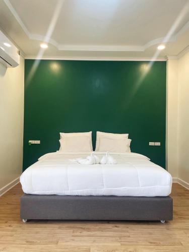 にあるNatcha Hotel and Residenceの緑の壁と大きなベッドのある寝室