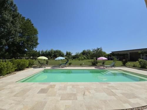 une grande piscine avec chaises et parasols dans l'établissement Charmant gîte en pierre avec piscine partagée, WiFi, proche de Bergerac - FR-1-616-490, à Lamonzie-Saint-Martin