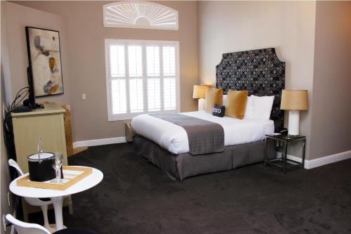 a bedroom with a large bed and a table and a window at Bel Abri Napa Valley Inn in Napa
