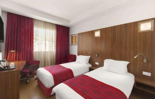 a hotel room with two beds and a desk at Ramada Encore By Wyndham Tangier in Tangier