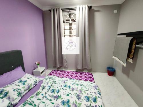 a bedroom with a bed with purple walls and a window at Zyara Homestay Seremban in Seremban