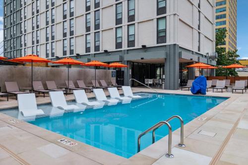 a swimming pool with chairs and umbrellas in front of a building at Hotel Indigo Chattanooga - Downtown by IHG in Chattanooga