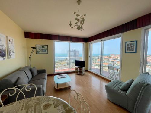 - un salon avec canapés, télévision et fenêtres dans l'établissement Studio face mer avec balcon et garage aux Sables d'Olonne - FR-1-92-904, à Les Sables-dʼOlonne