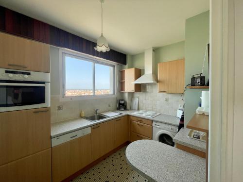 une cuisine avec un évier et une fenêtre dans l'établissement Studio face mer avec balcon et garage aux Sables d'Olonne - FR-1-92-904, à Les Sables-dʼOlonne