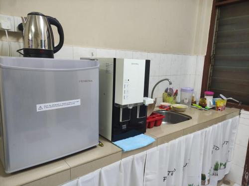 a kitchen counter with a microwave and a sink at Homestay Melaka Murah in Kampong Bertam