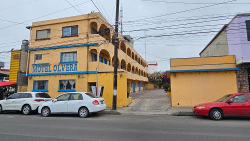 three cars parked in front of a yellow building at Motel Olvera in Tijuana