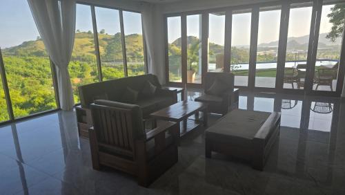 a living room with chairs and a table and windows at Villa Ayu Lombok in Kuta Lombok