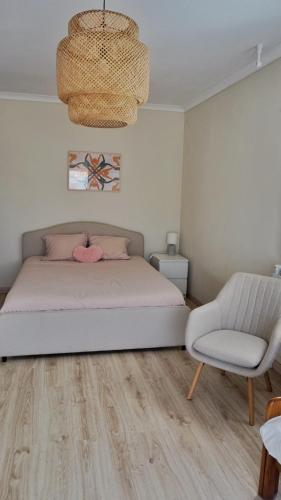 a bedroom with a bed and a chair and a chandelier at Casa Tucano in Aljezur