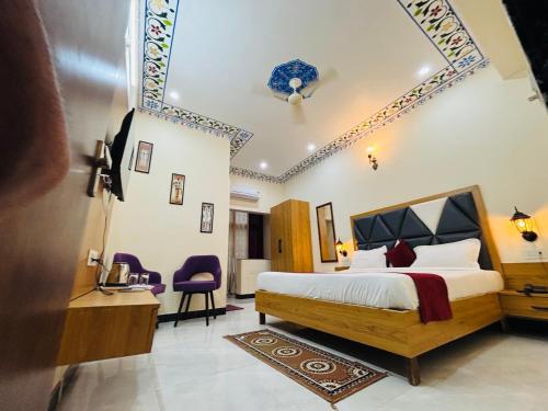 a bedroom with a bed and two purple chairs at Jai hari vilas in Jodhpur