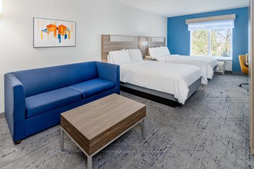 a hotel room with two beds and a blue couch at Holiday Inn Express & Suites Denver North - Thornton by IHG in Thornton