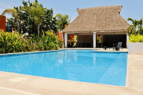 a large swimming pool with a thatch roof at Privada, Casa Real Flamingos , Nayarit in Bucerías