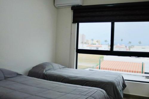 two beds in a room with a large window at Privada, Casa Real Flamingos , Nayarit in Bucerías