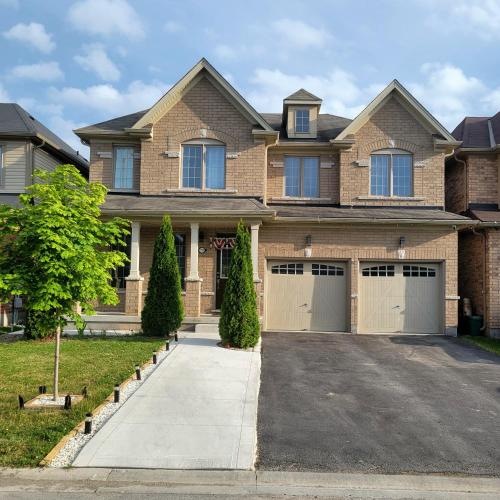 a large brick house with two garage doors at Luxury Suite - Master Bedroom in Niagara Falls