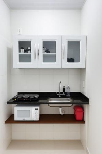 a kitchen with white cabinets and a sink and a microwave at Casa 4 min Parque do Sabia, UFU, Center Shopping in Uberlândia
