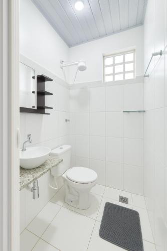 a white bathroom with a toilet and a sink at Casa 4 min Parque do Sabia, UFU, Center Shopping in Uberlândia