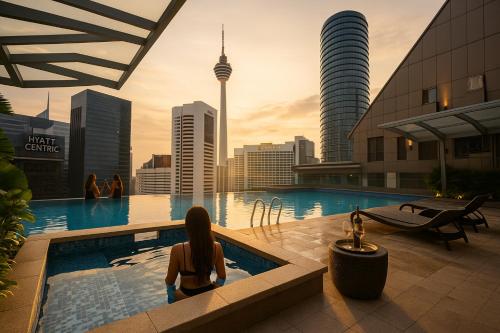a woman sitting in a pool with a view of a city at Cormar Suites Kuala Lumpur in Kuala Lumpur