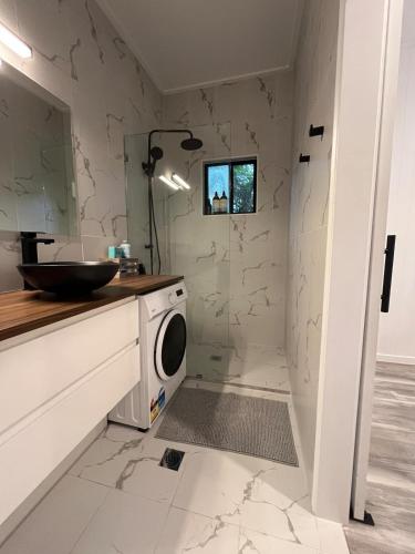 a bathroom with a sink and a washing machine at Cute and cosy 1 bedroom cabin in Mooloolah