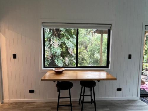 a table and two stools in front of a window at Cute and cosy 1 bedroom cabin in Mooloolah