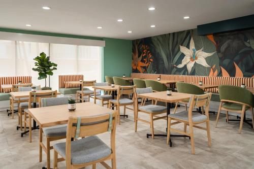 a restaurant with wooden tables and chairs and a painting at voco The Shelby - Myrtle Beach by IHG in Myrtle Beach