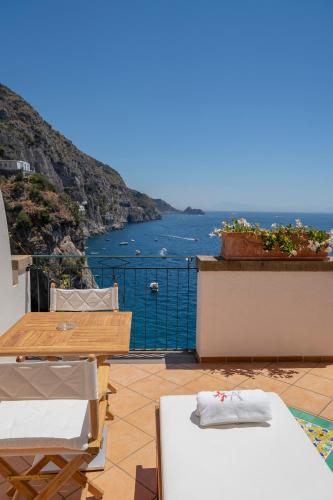 a balcony with a table and chairs and the ocean at Villa Corallium in Praiano