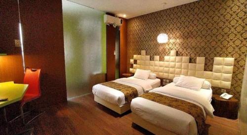 a hotel room with two beds and a desk at Griya Jogja Hotel in Yogyakarta