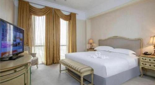 a bedroom with a large white bed and a flat screen tv at Zhejiang D.H Hotel in Jiaxing