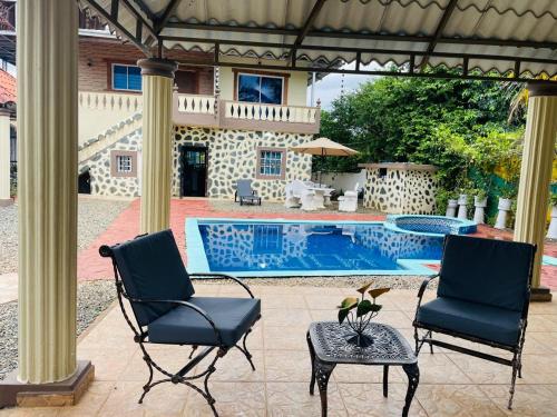deux chaises et une table à côté d'une piscine dans l'établissement Villa de Grupo 16, Piscina Natural, Jacuzzi, Granja y Mascotas, Rosa & Deivi te esperan, à Villa Altagracia