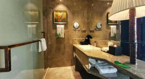 a bathroom with a sink and a counter with a mirror at Yongzhou Chuang Fa Cheng XiaoXiangYi Hotel in Guzhuting