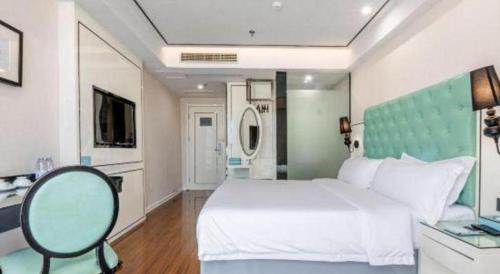 a bedroom with a large white bed and a chair at Xana Lite Anqing Yuexi Swan Squre Branch in Yuexi