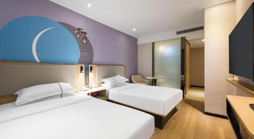 a hotel room with two beds and a flat screen tv at City Comfort Inn Xiao'gan City Beijing Road in Xiaogan