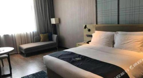 a hotel room with a bed and a chair at Echarm Hotel Changde Taoyuan Walking Street Jinyuan Tower in Changde