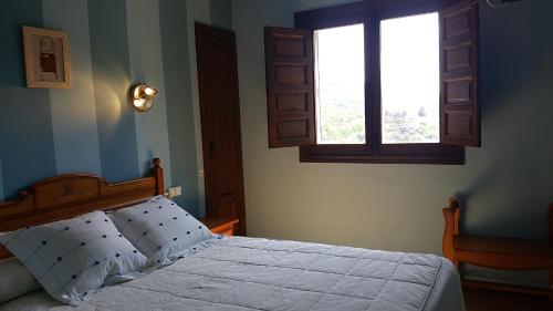 a bedroom with a bed and two windows at Hotel Judería Valle del Jerte in Cabezuela del Valle