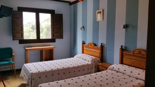 two twin beds in a room with a window at Hotel Judería Valle del Jerte in Cabezuela del Valle
