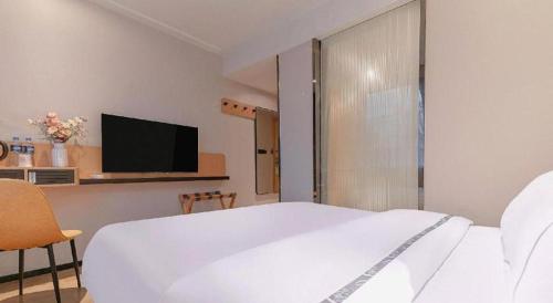 a bedroom with a white bed and a tv at City Comfort Inn Liuzhou High-speed Railway Station in Liuzhou