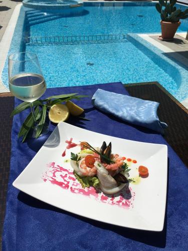 a plate of food on a table next to a swimming pool at Hotel Bellevue in Lignano Sabbiadoro
