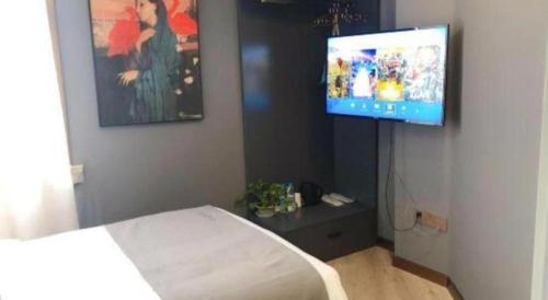 a bedroom with a bed and a flat screen tv at LANO Hotel Shandong Qingdao Jimo District Baolong Square in Qingdao