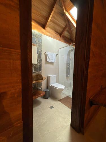 a bathroom with a toilet and a glass shower at Casa Campestre Los Nevados Patio Bonito in Estación El Salto