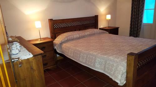een slaapkamer met een bed en twee nachtkastjes met lampen bij Casa da Beija - House Azores in Furnas