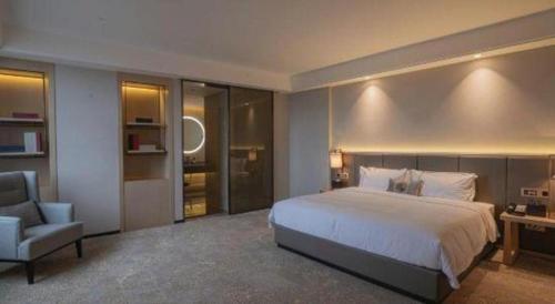 a bedroom with a large bed and a chair at E-Cheng Hotel Yangjiang Baili Plaza in Yangjiang