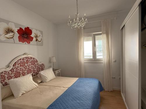 a bedroom with a bed and a chandelier at Apartamento Vacacional Manoli in Tarifa