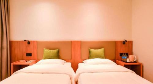 two beds in a room with green pillows at GreenTree Inn Express Lanzhou West Passenger Station Lanzhou Center in Lanzhou