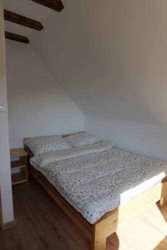 a bed in a room with a white wall at Słońce i cień in Baligród