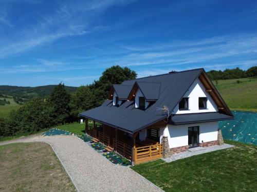 a small house with a black roof on a hill at Słońce i cień in Baligród