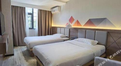a hotel room with two beds and a television at Borrman Hotel Yuxi Yuxing Road in Yuxi