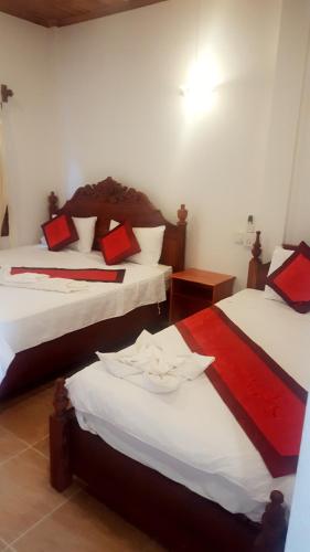 a room with two beds with red and white sheets at Villa Rattanakon in Luang Prabang
